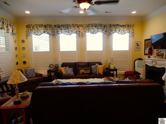 living room with visible vents, a fireplace, crown molding, and ceiling fan