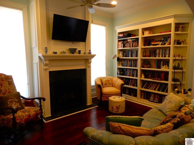 living area with crown molding, wood finished floors, a fireplace, and ceiling fan