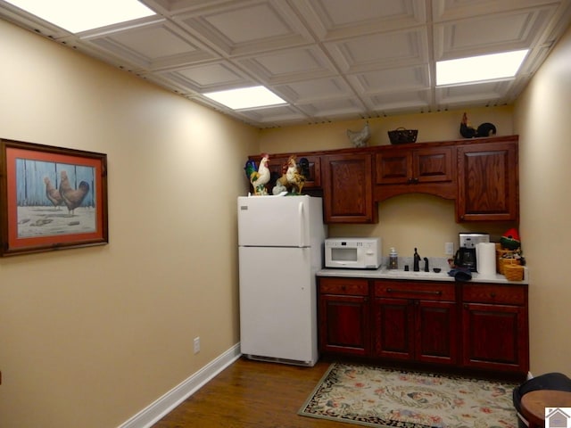 kitchen with baseboards, light countertops, wood finished floors, white appliances, and a sink