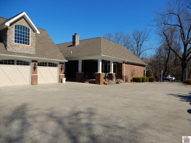 view of side of home with brick siding, driveway, and roof with shingles