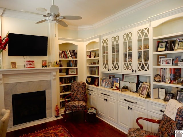 sitting room featuring a high end fireplace, a ceiling fan, dark wood-style floors, and crown molding