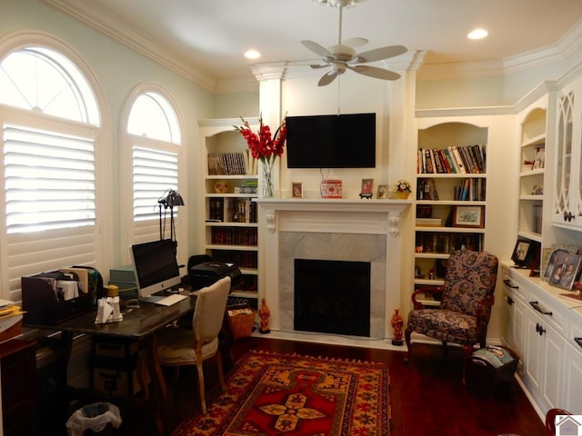 home office with built in features, a ceiling fan, wood finished floors, a fireplace, and ornamental molding