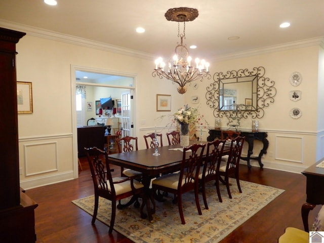 dining area with a wainscoted wall, ornamental molding, an inviting chandelier, wood finished floors, and a decorative wall