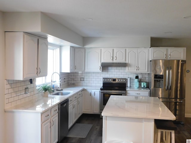 kitchen with under cabinet range hood, stainless steel appliances, white cabinetry, and a sink