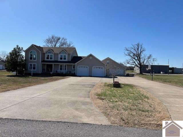 view of front of property featuring a garage, concrete driveway, and a front lawn