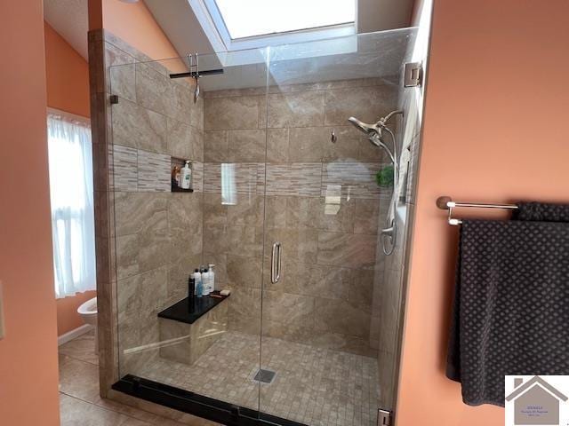 bathroom featuring tile patterned floors, toilet, a stall shower, and lofted ceiling with skylight