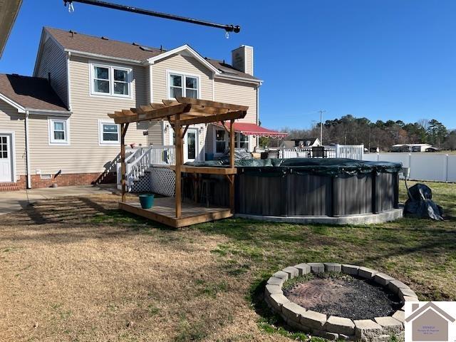 rear view of property with a lawn, a pergola, fence, a fire pit, and a wooden deck