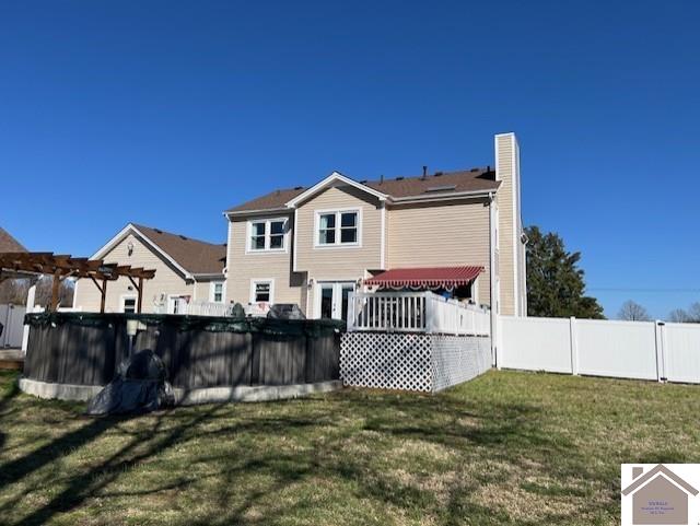 rear view of property with a fenced in pool, a pergola, a yard, and fence