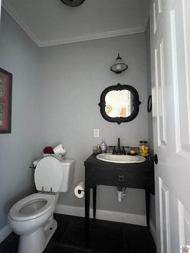 half bath featuring tile patterned flooring, crown molding, baseboards, toilet, and a sink