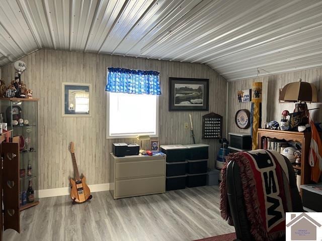 interior space with baseboards, wood finished floors, and vaulted ceiling