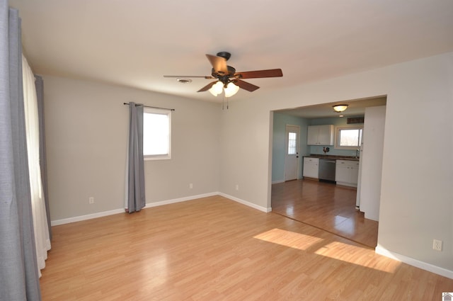 empty room with baseboards, light wood-type flooring, and ceiling fan