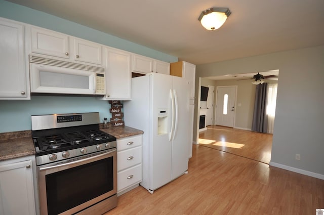 kitchen featuring white appliances, white cabinets, dark countertops, and light wood-type flooring