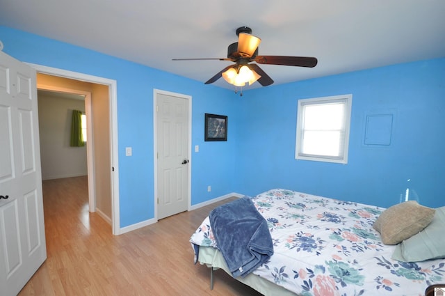 bedroom featuring light wood-style flooring, a ceiling fan, and baseboards