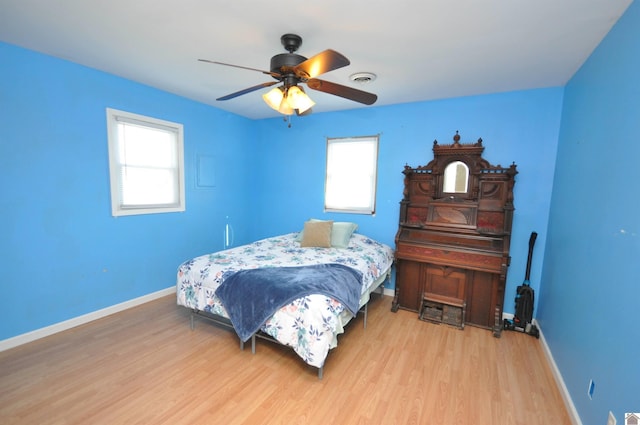 bedroom with multiple windows, baseboards, and wood finished floors