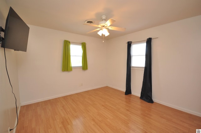 spare room featuring plenty of natural light, baseboards, and light wood-type flooring