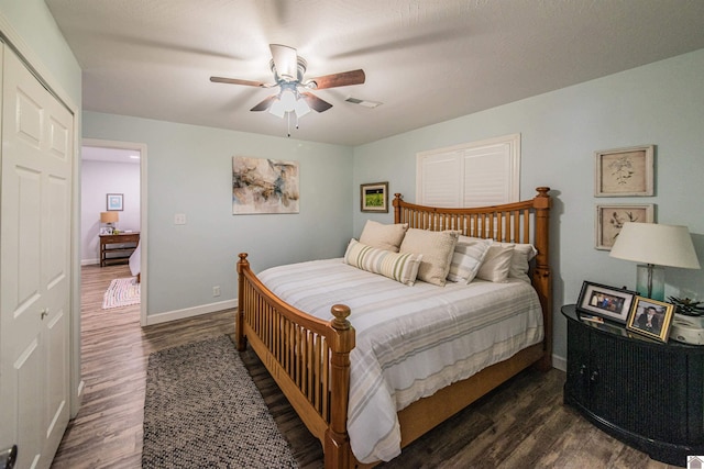 bedroom with dark wood-style floors, visible vents, a ceiling fan, and baseboards