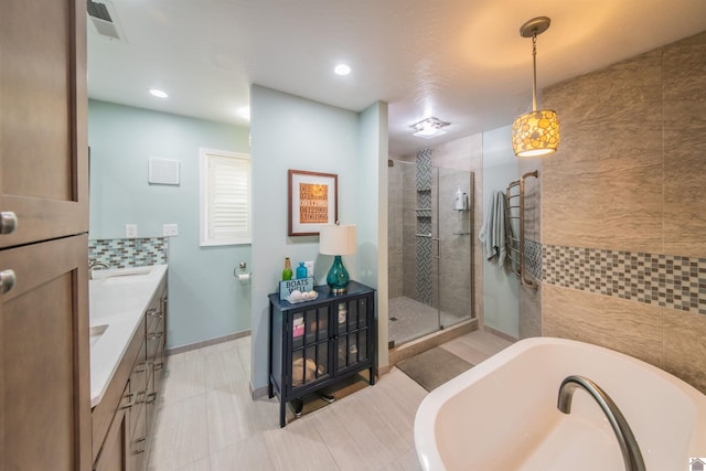 full bathroom with visible vents, baseboards, tiled shower, a freestanding tub, and vanity