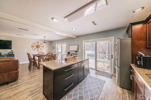 kitchen with light wood-type flooring, visible vents, plenty of natural light, and freestanding refrigerator