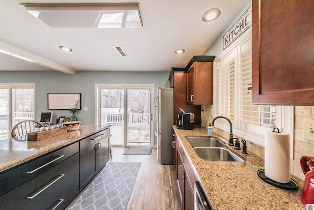 kitchen featuring a sink, visible vents, plenty of natural light, and freestanding refrigerator