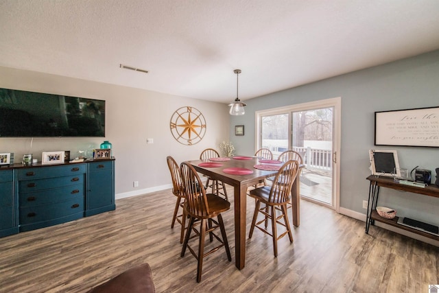 dining room featuring visible vents, a textured ceiling, baseboards, and wood finished floors