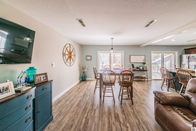 dining area with visible vents, a textured ceiling, and wood finished floors