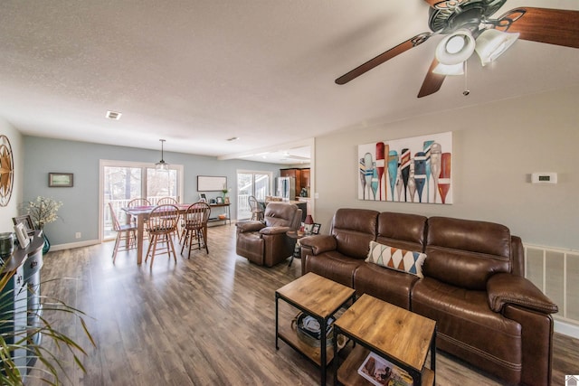 living room with visible vents, baseboards, a textured ceiling, and wood finished floors