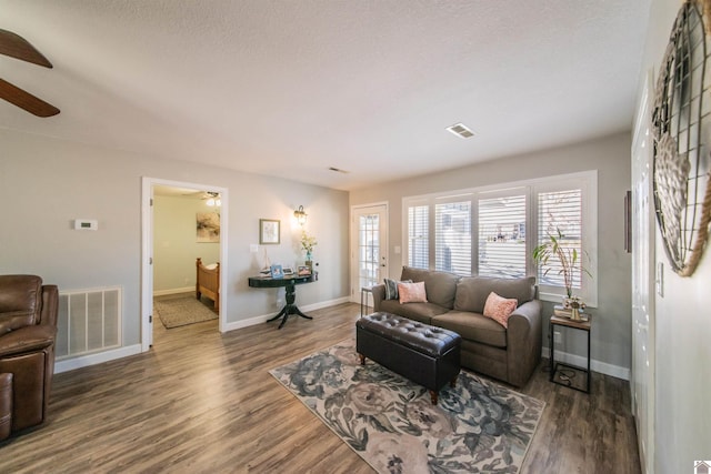 living area with wood finished floors, visible vents, and baseboards