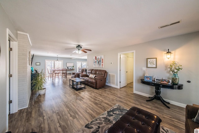 living room featuring visible vents, ceiling fan, baseboards, and wood finished floors