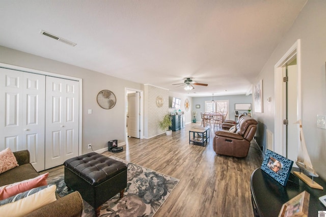 living area featuring visible vents, baseboards, and wood finished floors