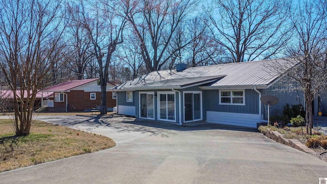 ranch-style home with driveway and metal roof