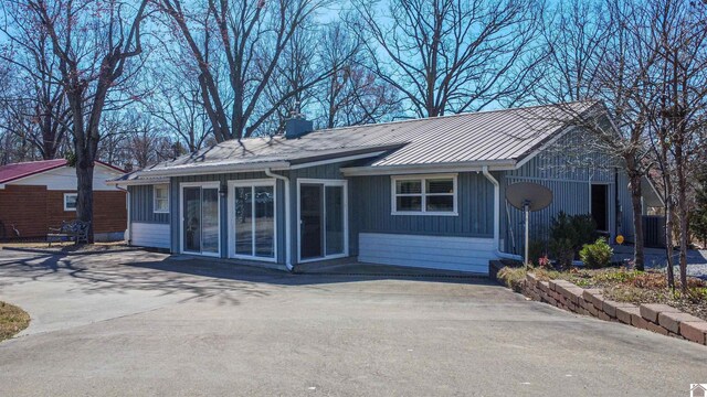 rear view of property with a standing seam roof, a chimney, and metal roof