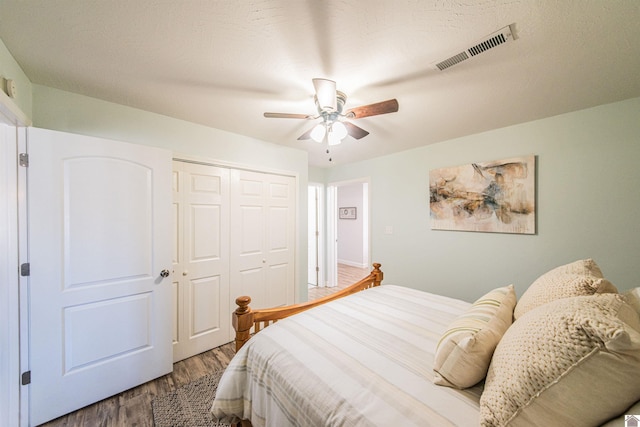 bedroom featuring wood finished floors, visible vents, a closet, and ceiling fan