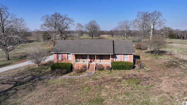 single story home with brick siding, covered porch, and driveway