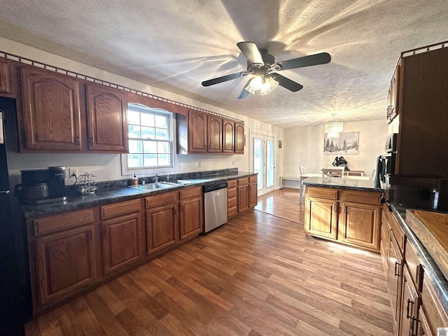 kitchen with a sink, dark countertops, dishwasher, and wood finished floors