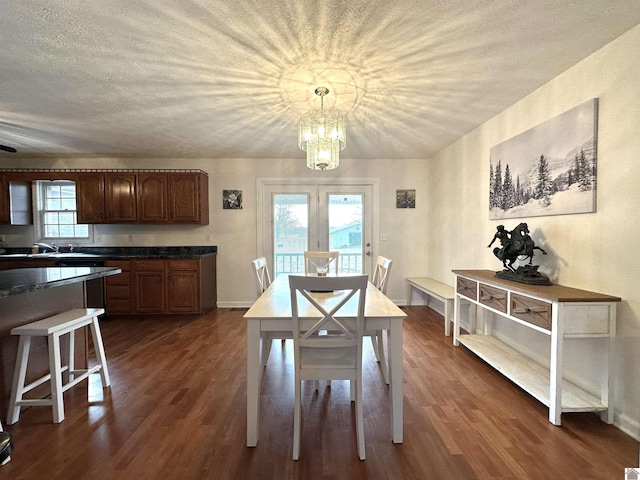 dining area with a notable chandelier, baseboards, a textured ceiling, and dark wood finished floors