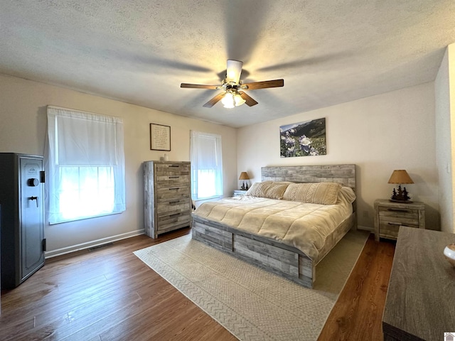 bedroom with dark wood finished floors, visible vents, multiple windows, and a textured ceiling