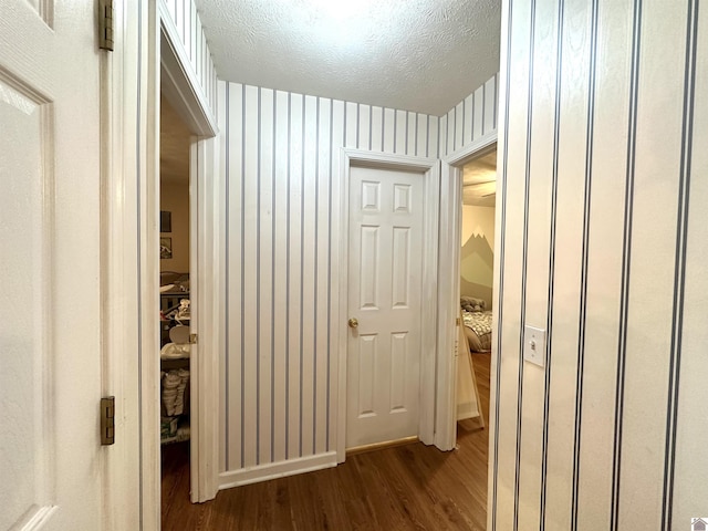 corridor with a textured ceiling and dark wood-style flooring