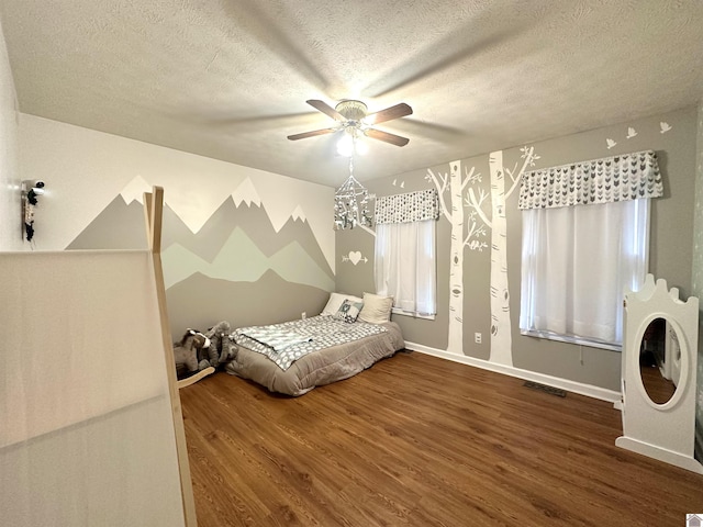 unfurnished bedroom with a ceiling fan, baseboards, wood finished floors, visible vents, and a textured ceiling