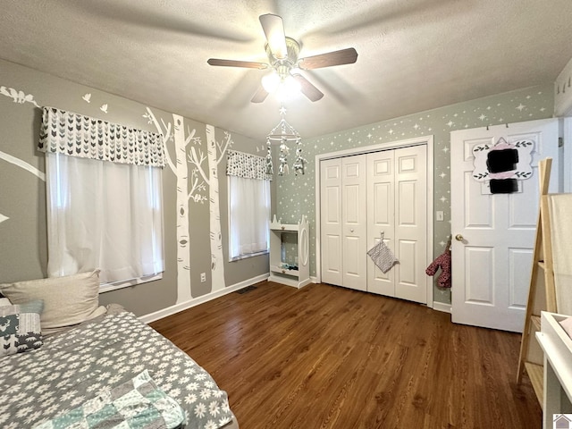 bedroom with wallpapered walls, wood finished floors, baseboards, and a textured ceiling