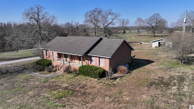 exterior space featuring a porch, brick siding, and a front lawn