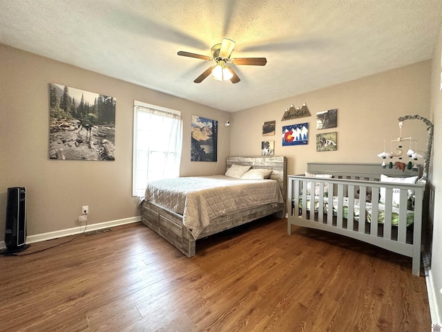 bedroom featuring baseboards, a textured ceiling, and wood finished floors