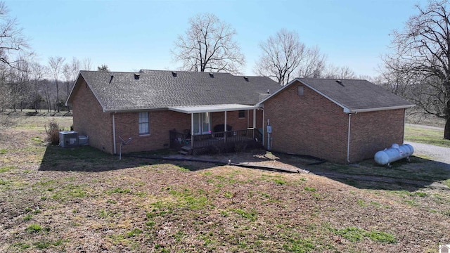 rear view of property with central air condition unit, brick siding, and a shingled roof