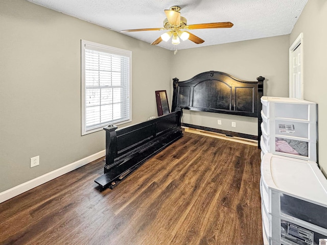 bedroom with ceiling fan, a textured ceiling, dark wood-type flooring, and baseboards