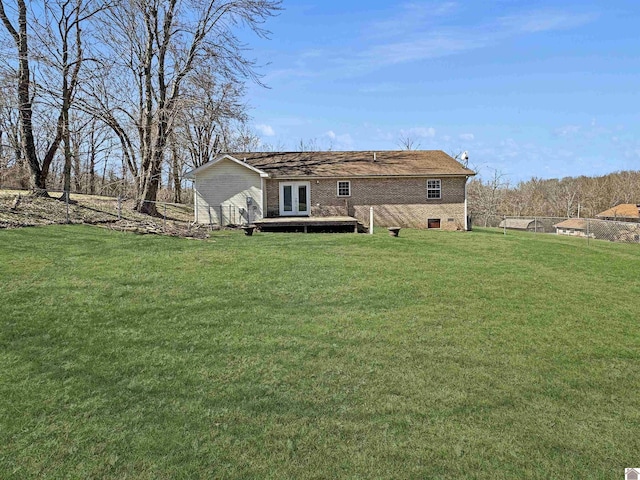 rear view of house with fence, a lawn, brick siding, and french doors