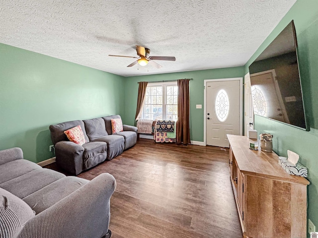 living area featuring dark wood finished floors, ceiling fan, a textured ceiling, and baseboards