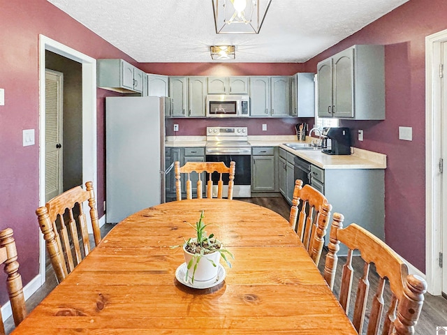 kitchen with a sink, stainless steel appliances, a textured ceiling, and light countertops