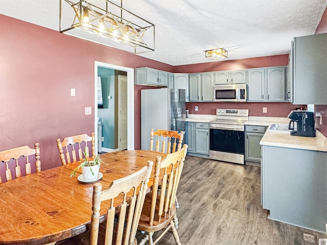 kitchen with light countertops, light wood-type flooring, appliances with stainless steel finishes, and a textured ceiling