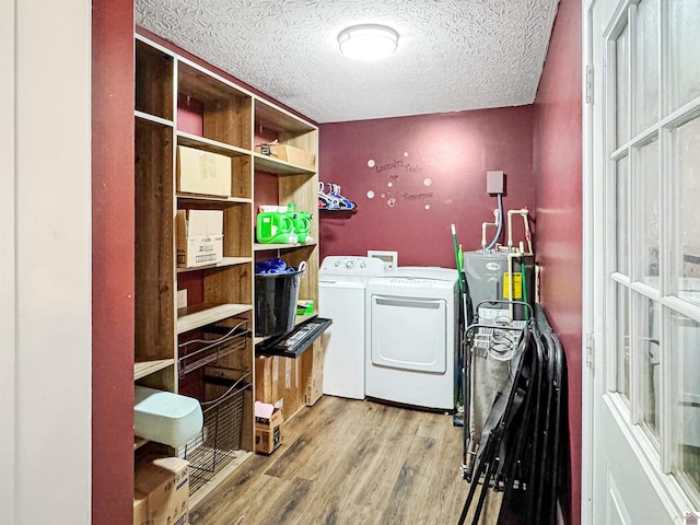 laundry room with washing machine and dryer, water heater, laundry area, wood finished floors, and a textured ceiling