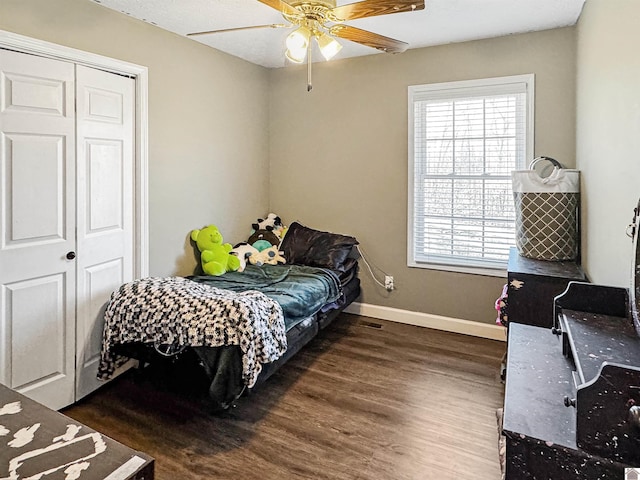 bedroom with a closet, baseboards, wood finished floors, and a ceiling fan