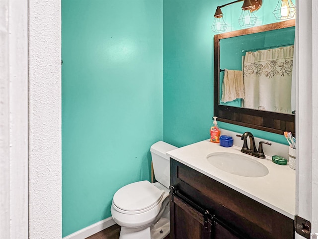 full bath featuring toilet, vanity, and baseboards